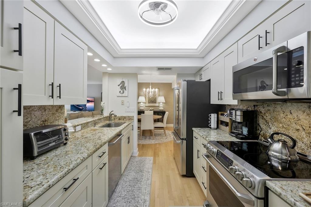 Kitchen featuring decorative backsplash, stainless steel appliances, light wood-style floors, light stone counters, and recessed lighting
