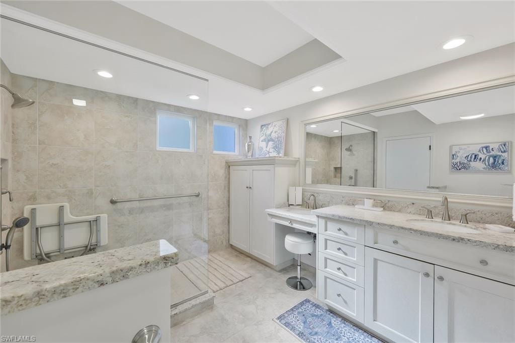 Bathroom featuring tile walls, a walk in shower, vanity, and recessed lighting