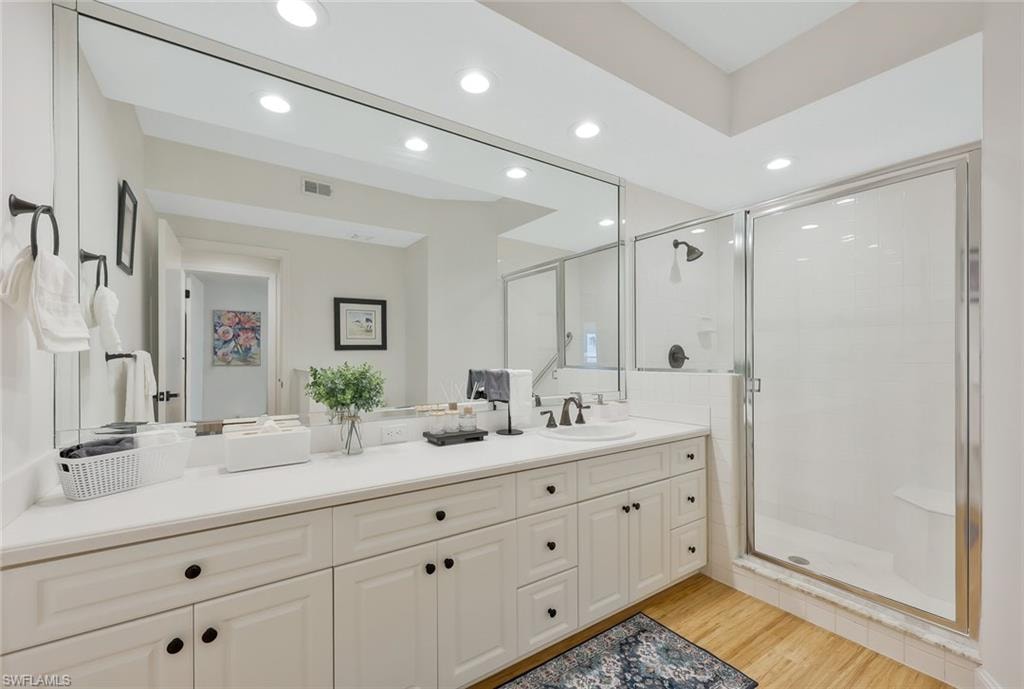 Bathroom with a stall shower, vanity, light wood-type flooring, and recessed lighting