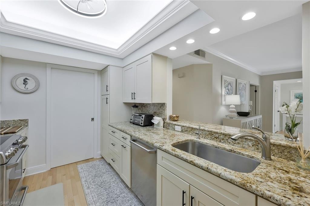 Kitchen with stainless steel appliances, recessed lighting, light wood-style floors, crown molding, and light stone countertops