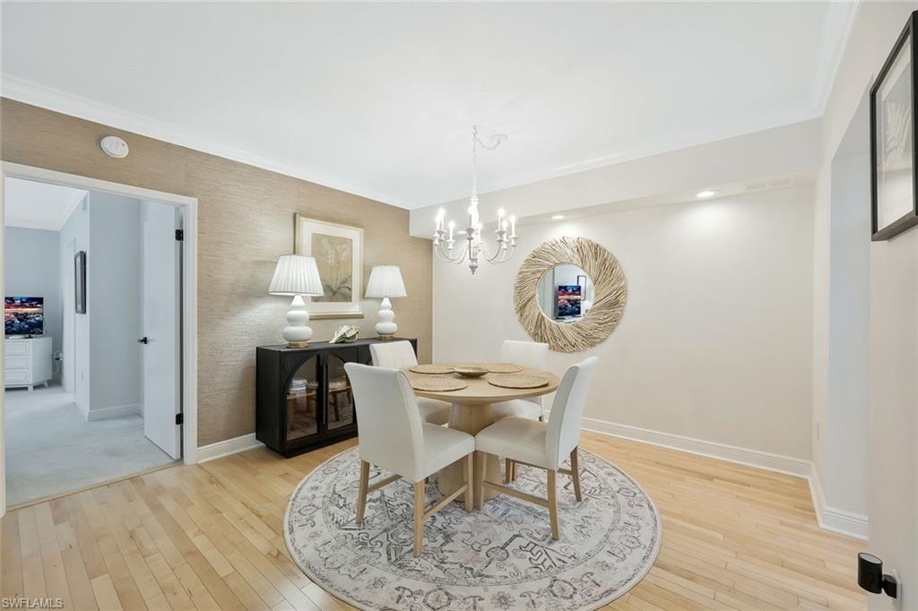 Dining room featuring ornamental molding, light wood-style floors, and a chandelier
