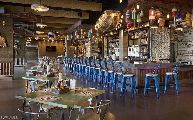 Community bar area with dark countertops and beam ceiling