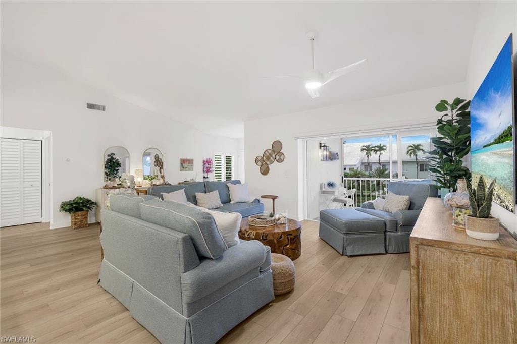Living room with lofted ceiling, light vinyl plank flooring, and a ceiling fan