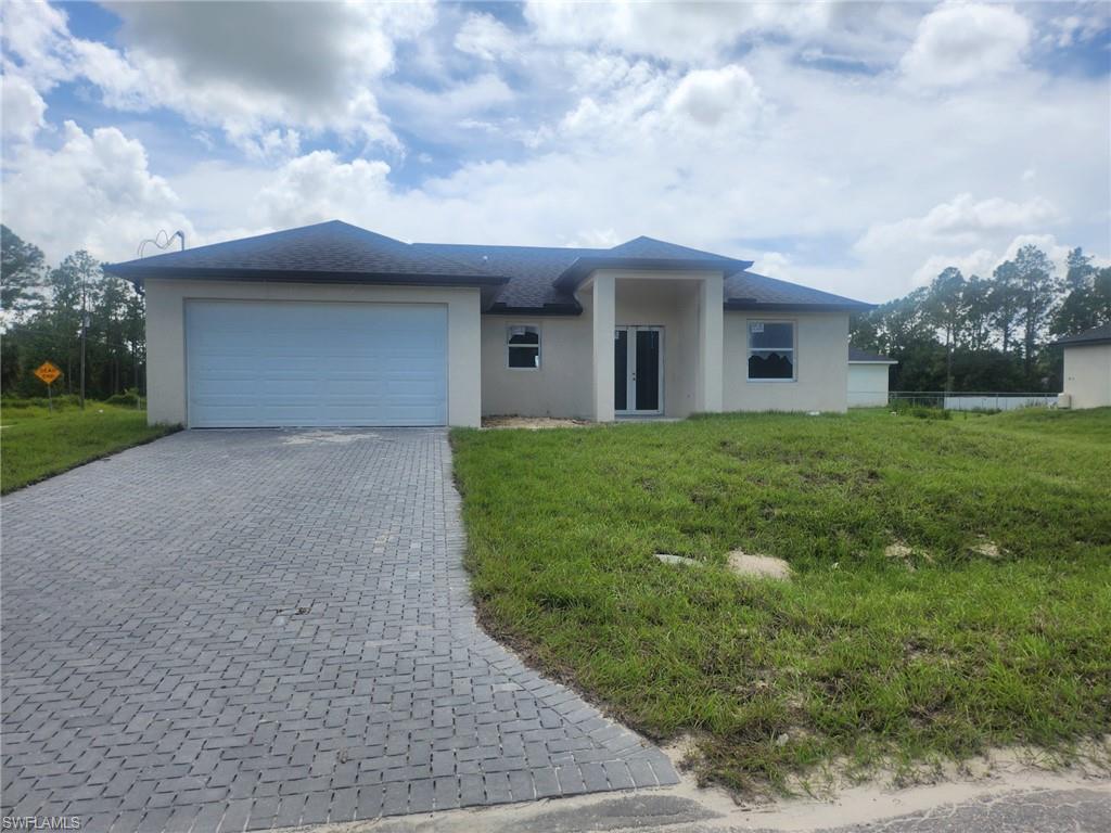 Single story home with stucco siding, decorative driveway, an attached garage, and a front yard