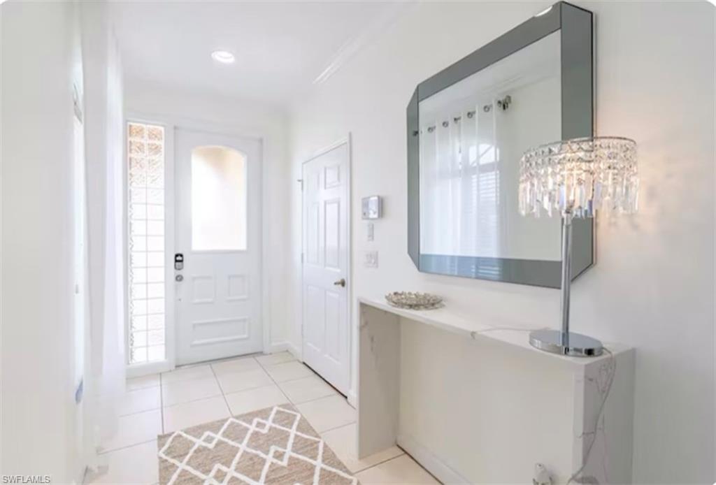 Entrance foyer featuring light tile patterned floors and crown molding