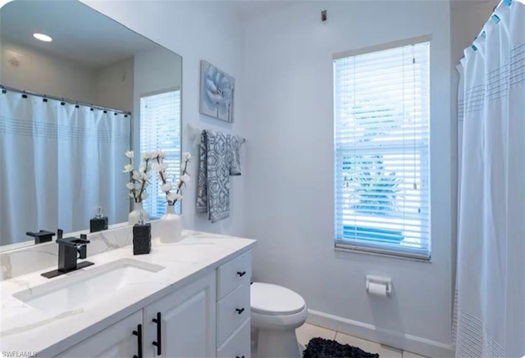 Full bath featuring vanity, light tile patterned floors, and a shower with shower curtain