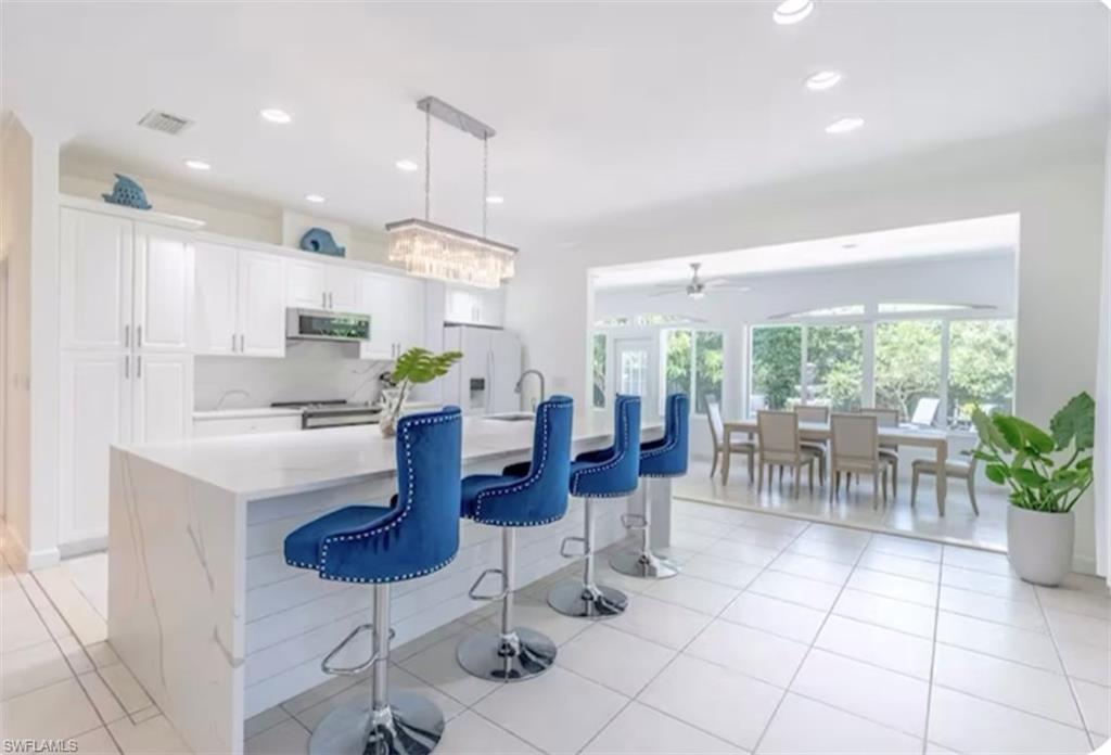 Kitchen featuring white cabinetry, light tile patterned flooring, decorative light fixtures, recessed lighting, and a breakfast bar