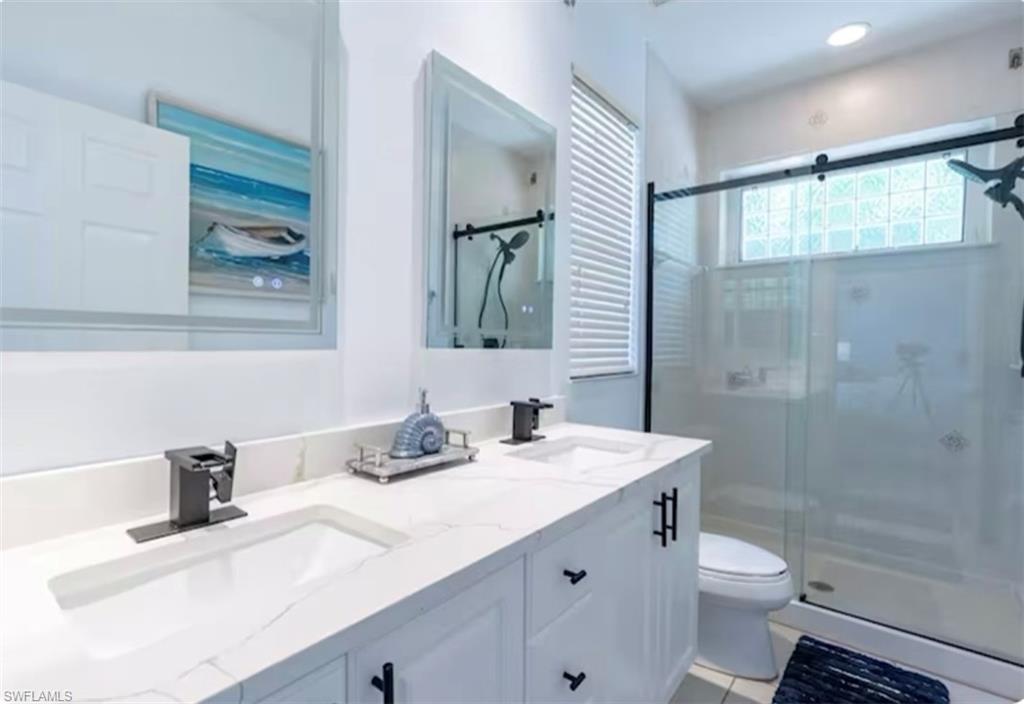 Bathroom featuring a stall shower, double vanity, and light tile patterned floors