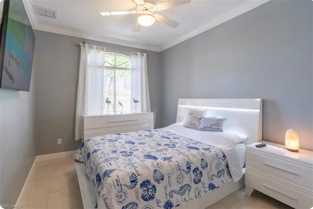Bedroom with ornamental molding, light tile patterned floors, and a ceiling fan