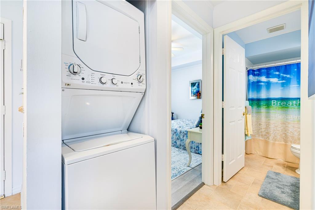 Washroom featuring stacked washing machine and dryer and light tile patterned flooring