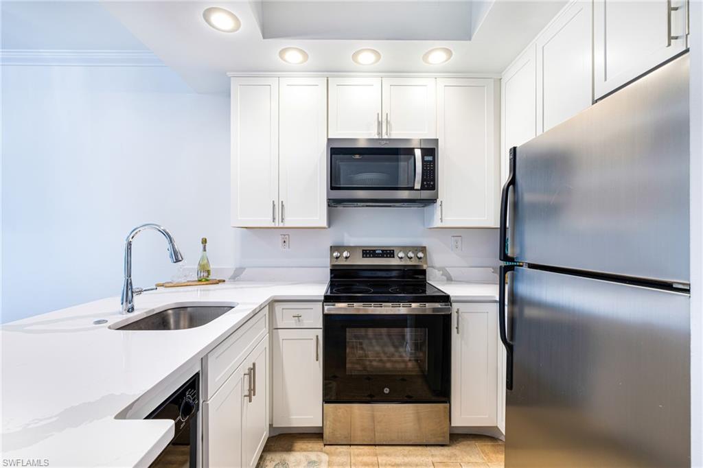 Kitchen featuring stainless steel appliances, white cabinetry, light stone countertops, light tile patterned floors, and recessed lighting
