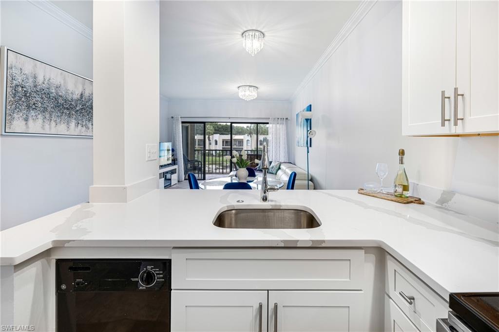 Kitchen with crown molding, white cabinetry, black dishwasher, light stone countertops, and open floor plan
