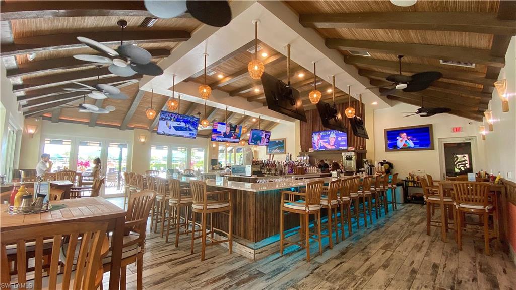 Bar with beamed ceiling, hardwood / wood-style floors, ceiling fan, and high vaulted ceiling