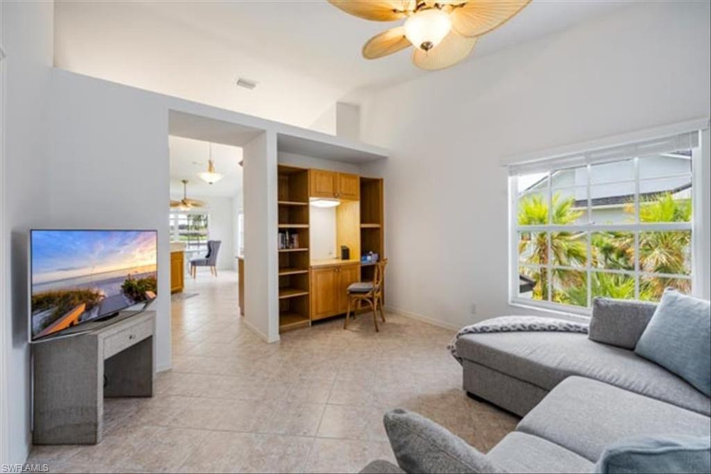 Tiled living room featuring ceiling fan and vaulted ceiling