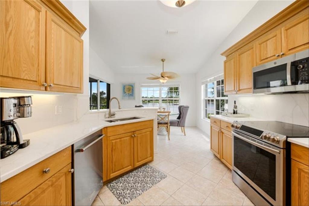 Kitchen featuring appliances with stainless steel finishes, lofted ceiling, sink, and ceiling fan