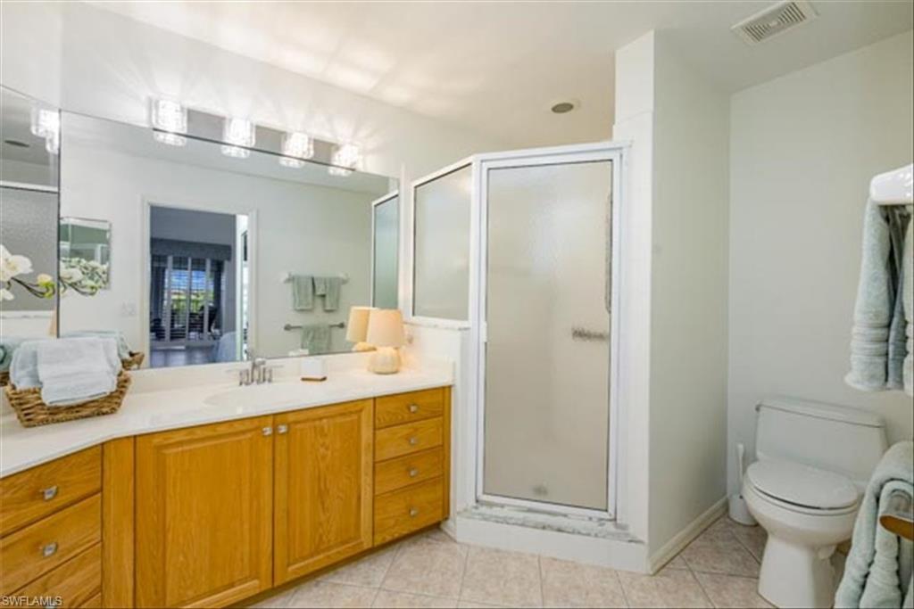 Bathroom with vanity, toilet, tile patterned floors, and a shower with door
