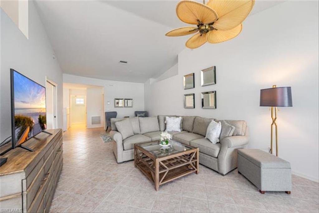 Tiled living room featuring lofted ceiling and ceiling fan