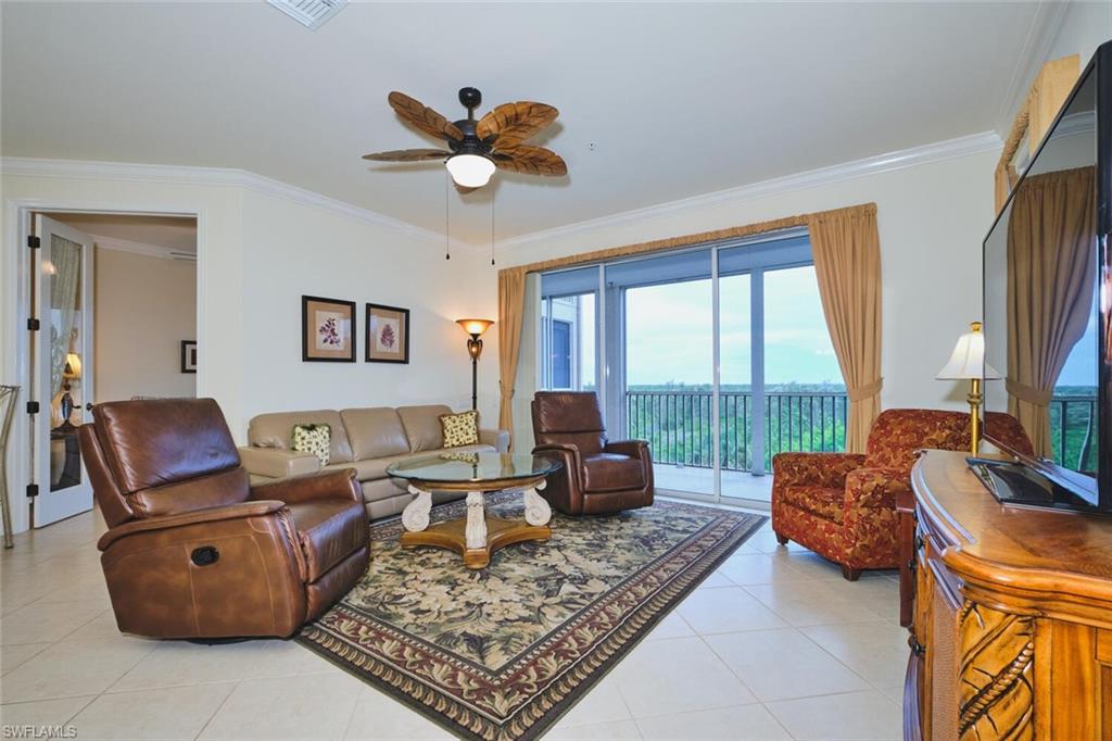 Living area with ornamental molding, light tile patterned flooring, and ceiling fan