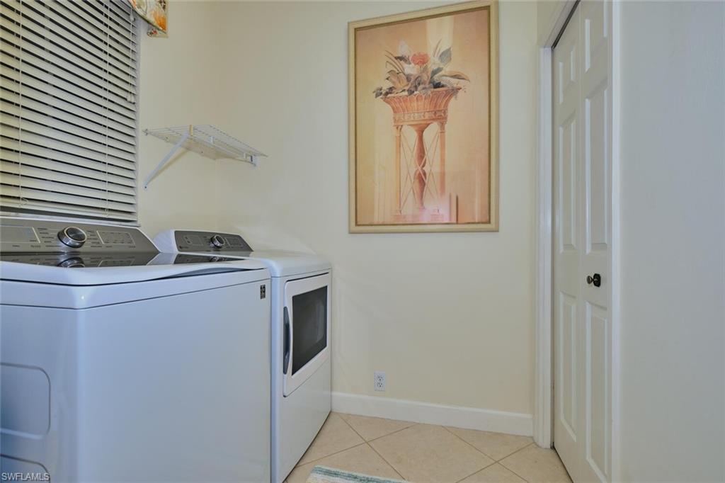Laundry room featuring light tile patterned floors and washing machine and dryer
