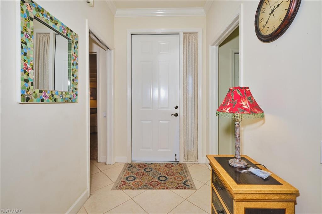 Foyer with light tile patterned floors and ornamental molding