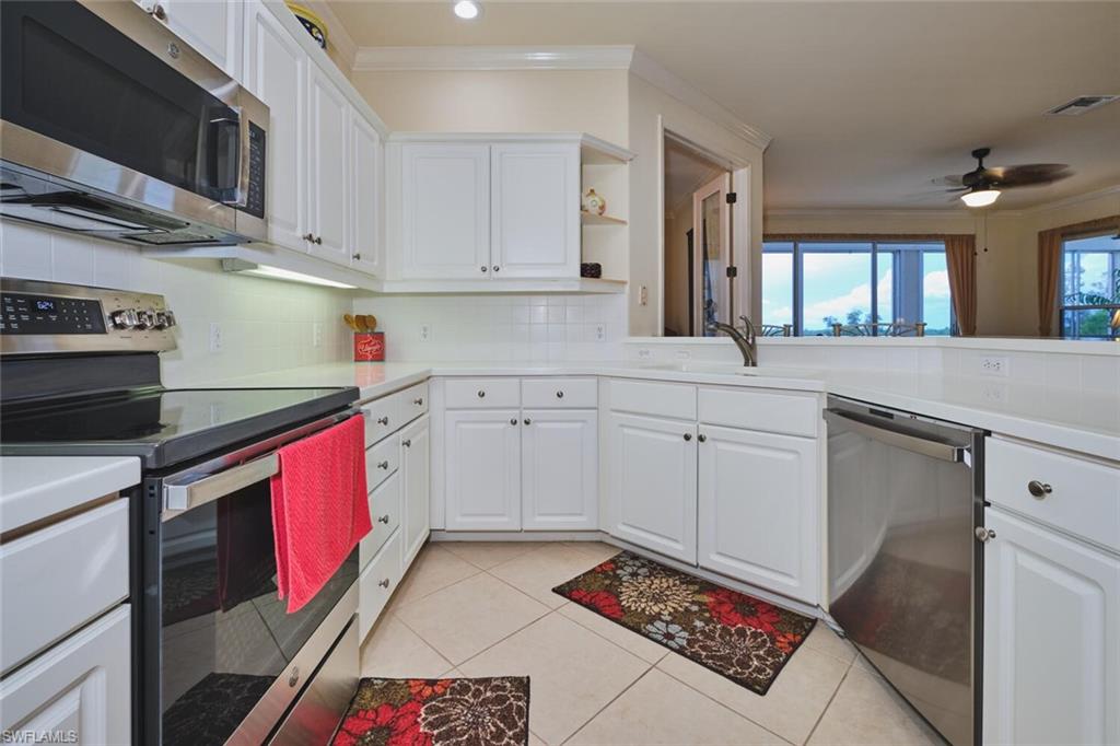 Kitchen with stainless steel appliances, white cabinetry, tasteful backsplash, ornamental molding, and light tile patterned floors