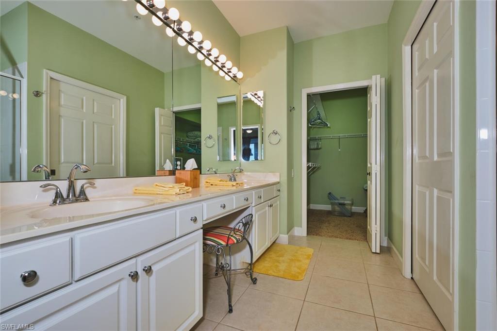 Full bathroom featuring light tile patterned floors, double vanity, and a walk in closet
