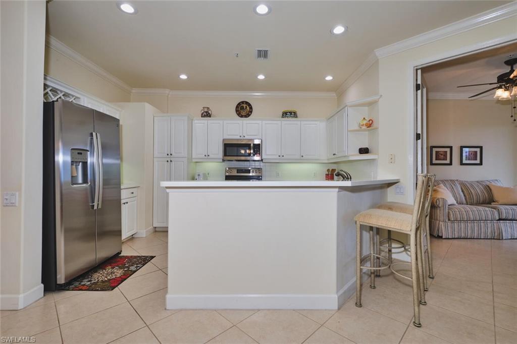 Kitchen featuring stainless steel appliances, white cabinets, crown molding, open shelves, and light tile patterned floors