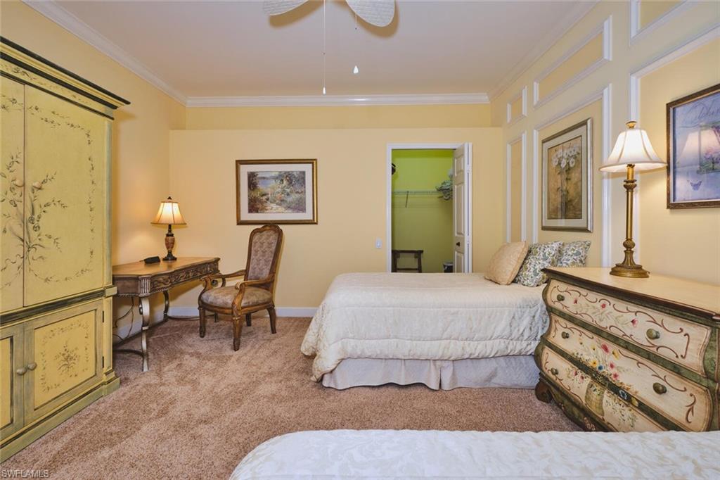 Bedroom with a spacious closet, ornamental molding, light carpet, and ceiling fan