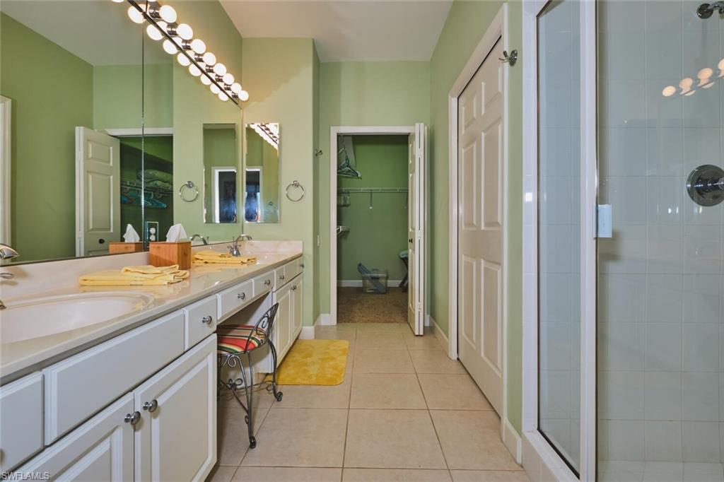Bathroom featuring double vanity, light tile patterned floors, and a stall shower