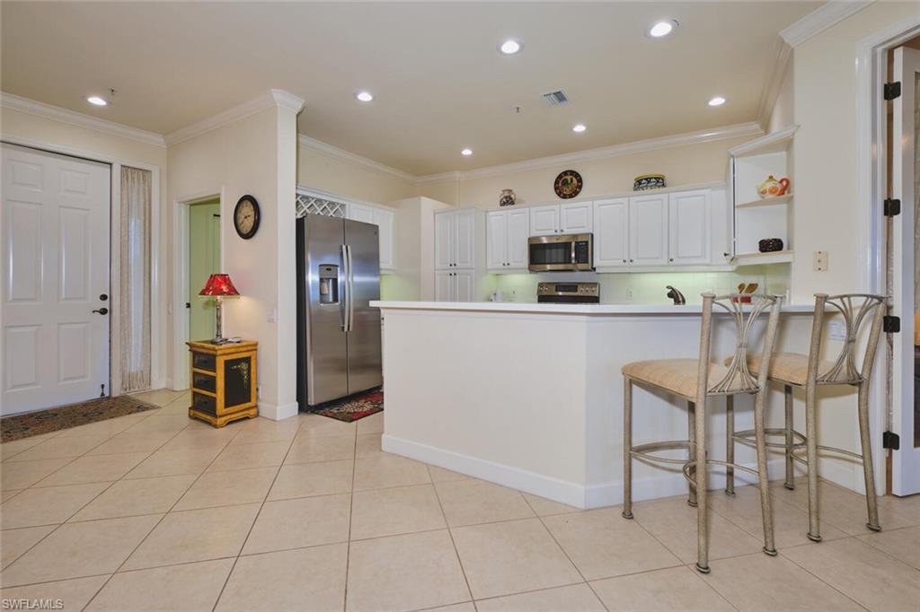 Kitchen featuring white cabinetry, stainless steel appliances, crown molding, recessed lighting, and a peninsula