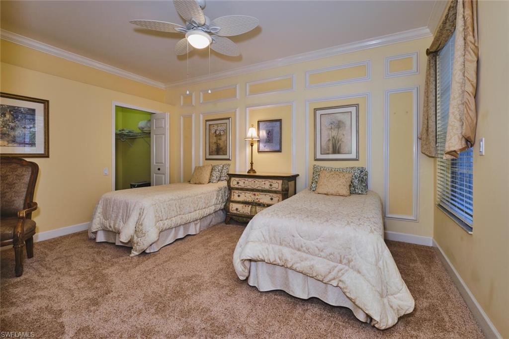 Bedroom with carpet floors, crown molding, a spacious closet, and a ceiling fan