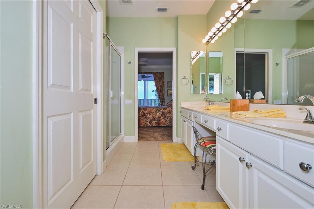 Ensuite bathroom with a stall shower, double vanity, and light tile patterned floors