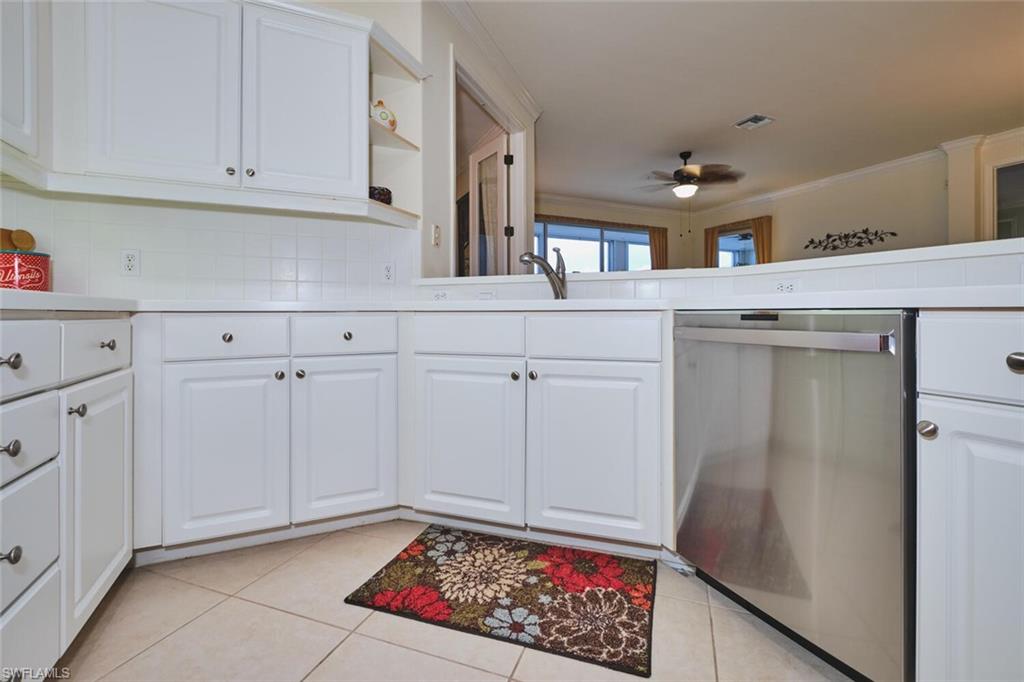 Kitchen with white cabinets, dishwasher, light countertops, light tile patterned flooring, and open shelves