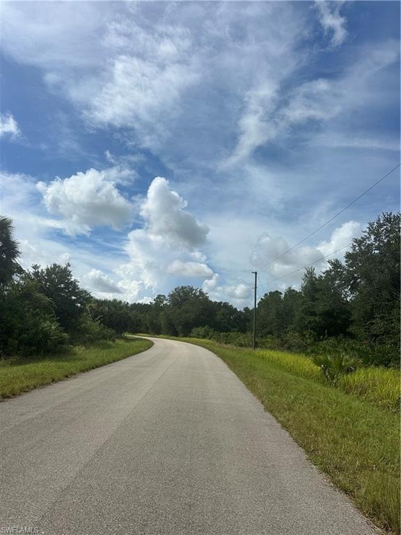 View of asphalt street featuring a wooded view