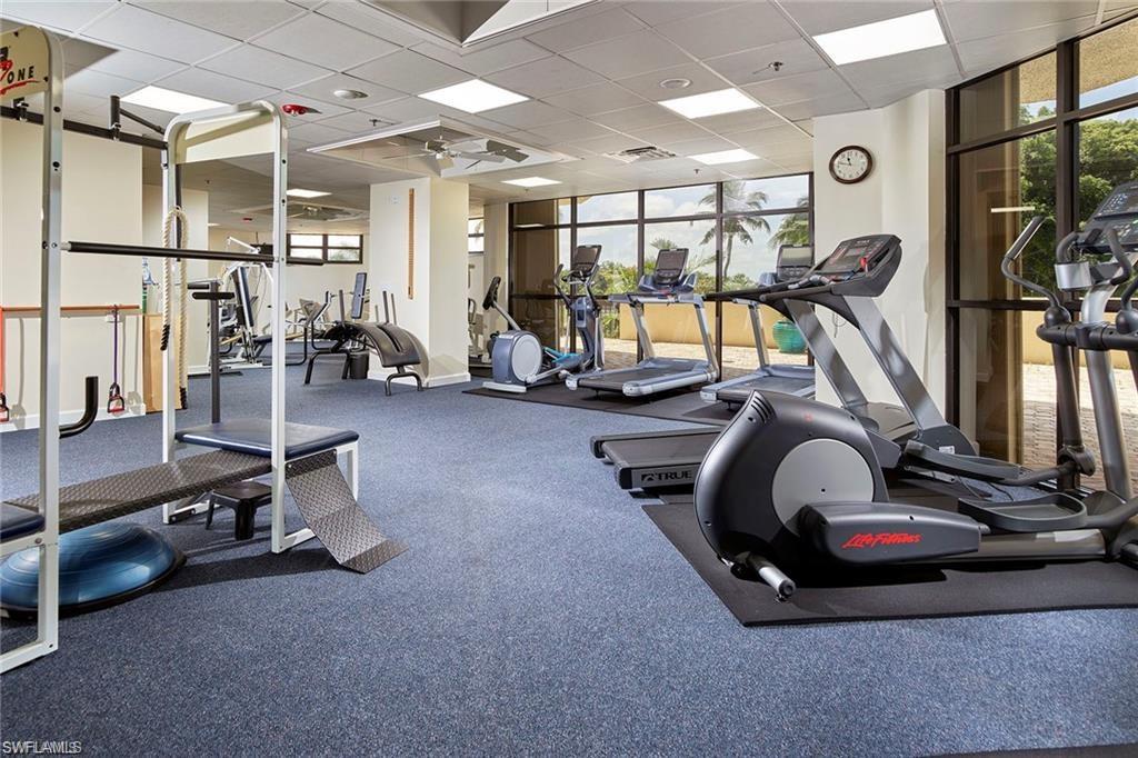 Workout area featuring expansive windows, plenty of natural light, a drop ceiling, and ceiling fan