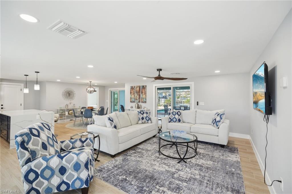 Living room with recessed lighting, light wood-type flooring, and a ceiling fan