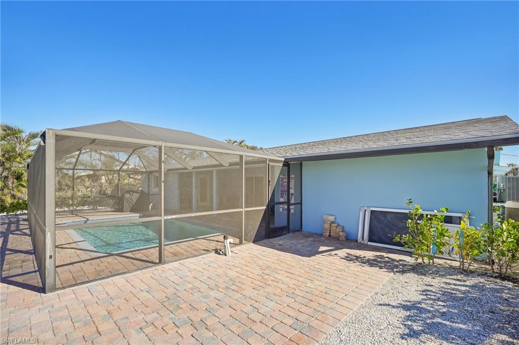 Rear view of property with a sunroom, a patio area, stucco siding, an outdoor pool, and glass enclosure