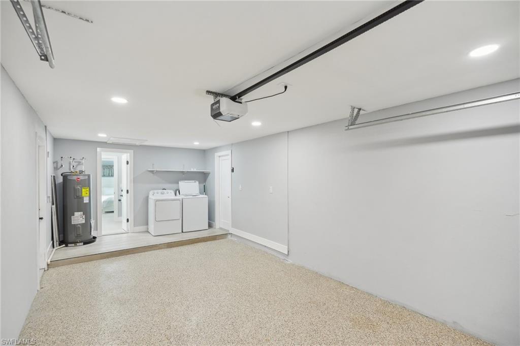 Garage with recessed lighting, washing machine and clothes dryer, electric water heater, and a garage door opener