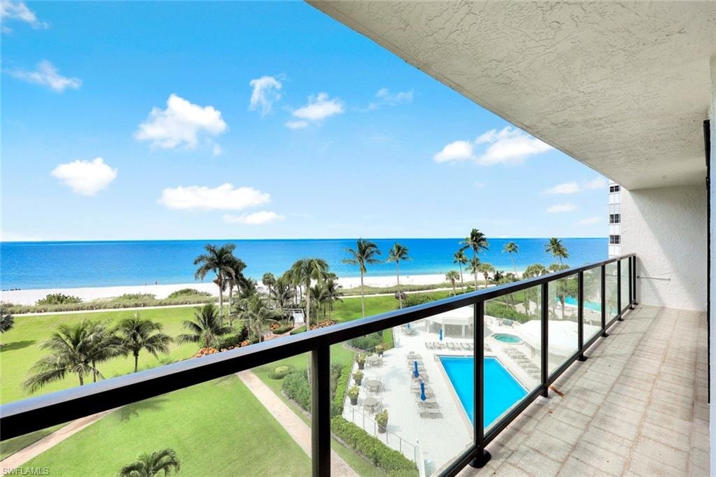 Balcony featuring view of pool area and view of water and beach