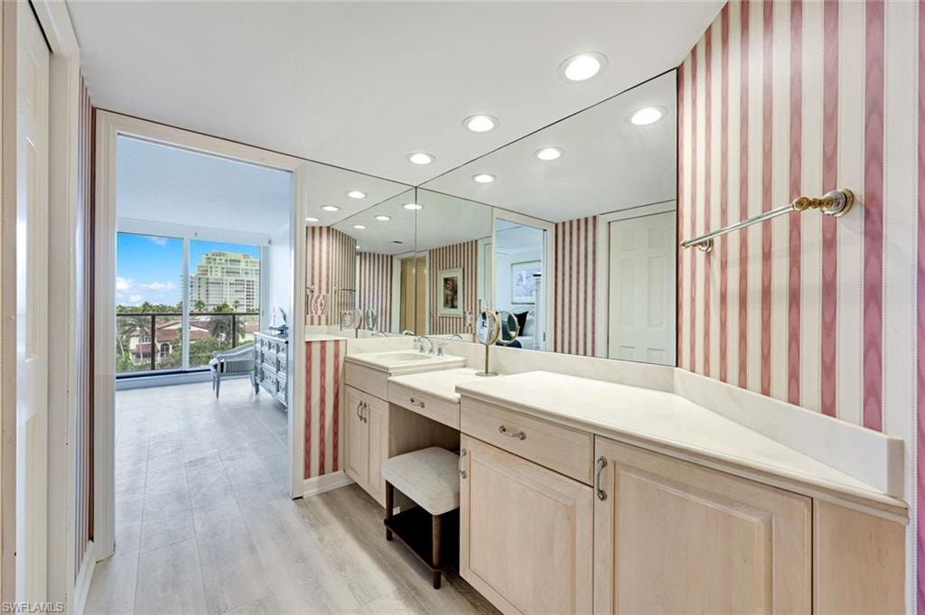 Bathroom with recessed lighting, wallpapered walls, floor to ceiling windows, light wood finished floors, and vanity