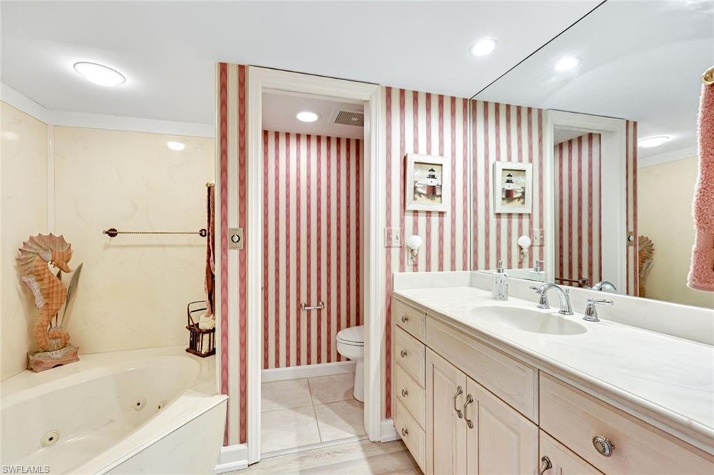 Bathroom with vanity, wallpapered walls, a jetted tub, light tile patterned flooring, and recessed lighting
