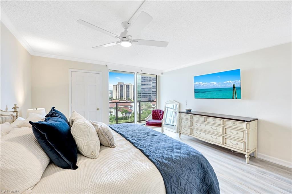 Bedroom featuring a textured ceiling, light wood-style floors, a ceiling fan, expansive windows, and ornamental molding