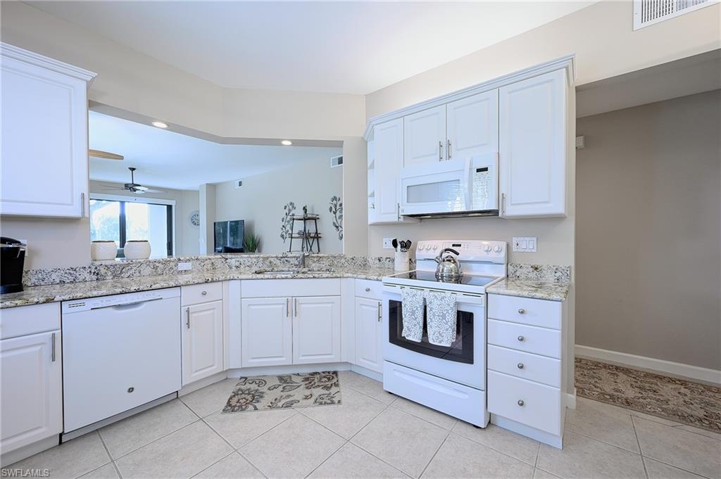 Kitchen featuring white cabinets, light tile patterned floors, and white appliances