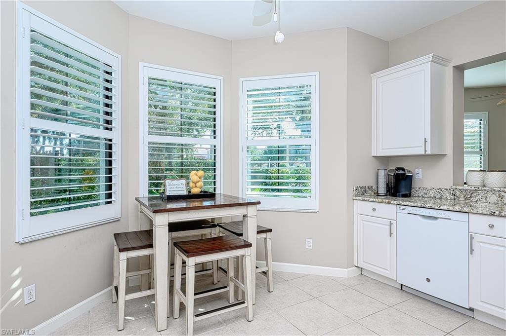 Kitchen featuring dishwasher, light stone counters, white cabinetry, light tile patterned floors, and ceiling fan