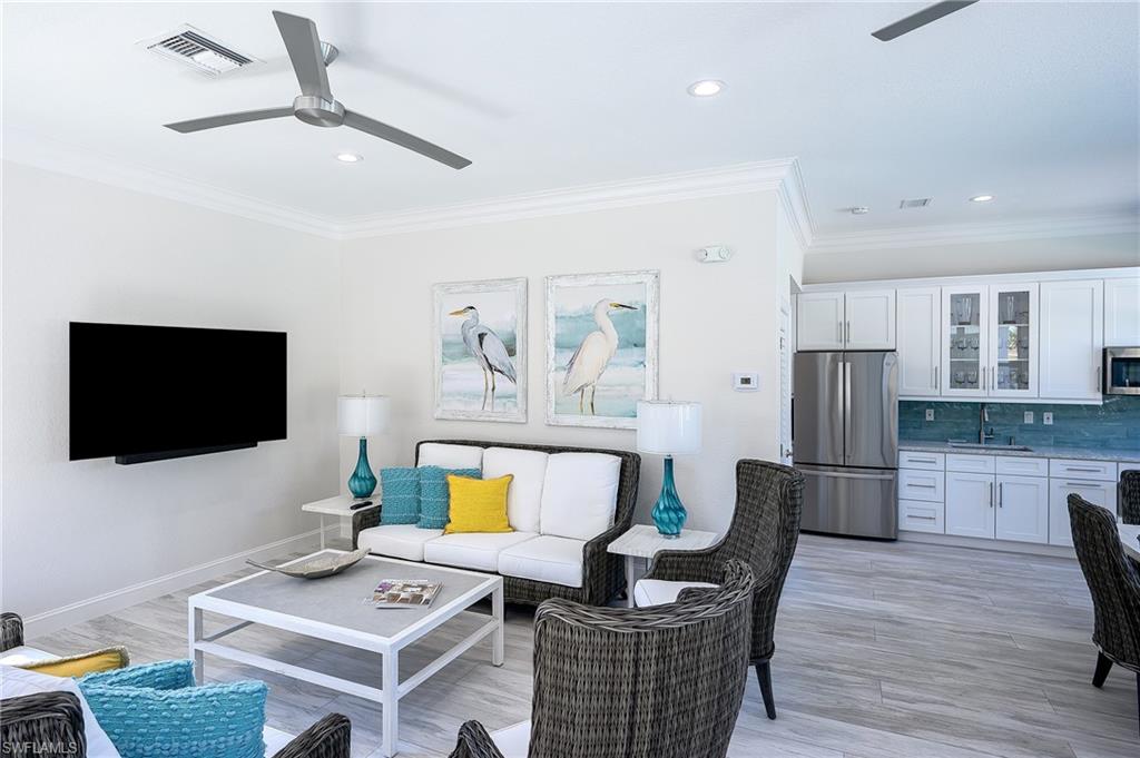 Living room with ceiling fan, ornamental molding, light wood-type flooring, and sink