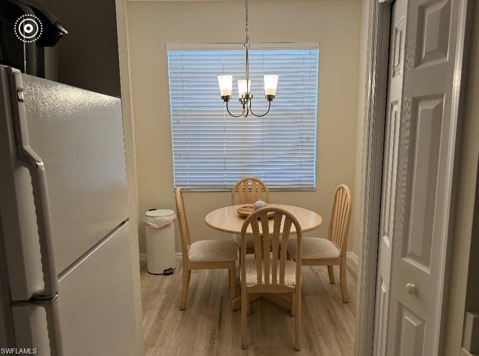 Dining room with light wood-style flooring and a chandelier