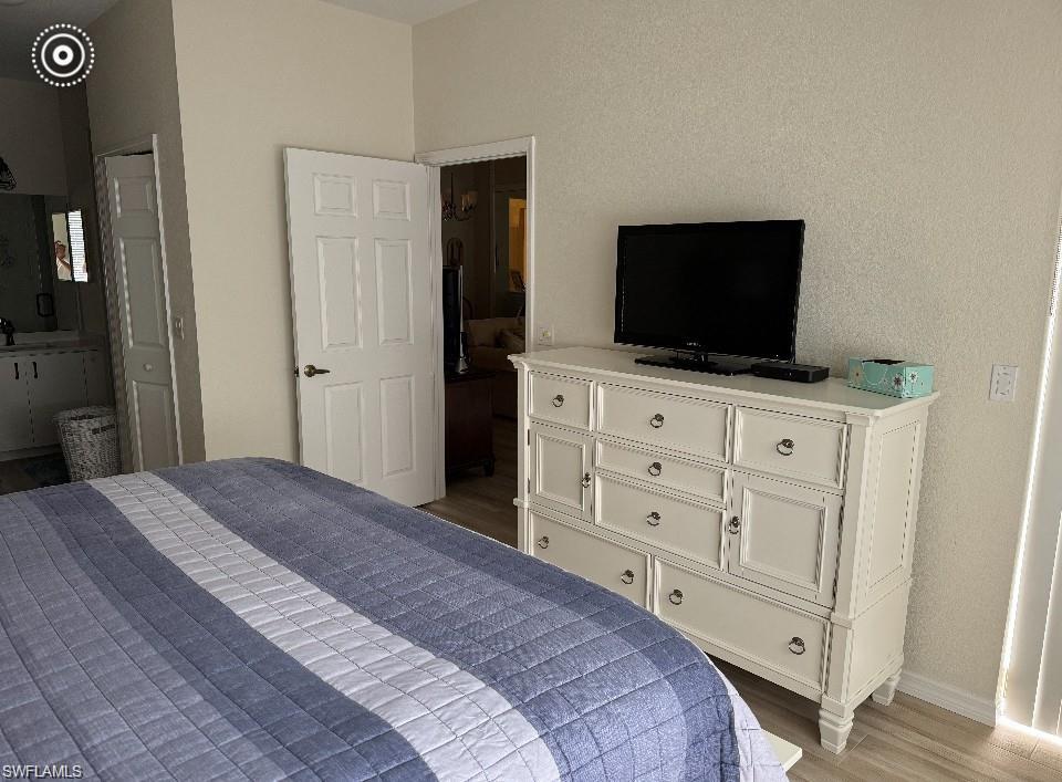Bedroom featuring wood finished floors, ensuite bath, and a textured wall
