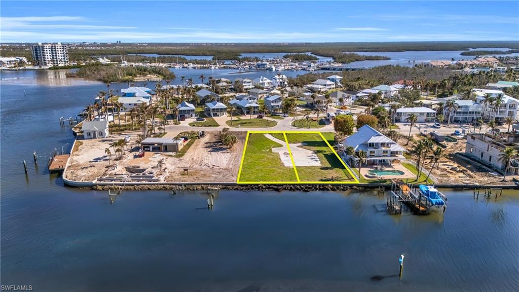 Aerial view of residential area featuring a large body of water and property parcel outlined - Virtually Edited Image