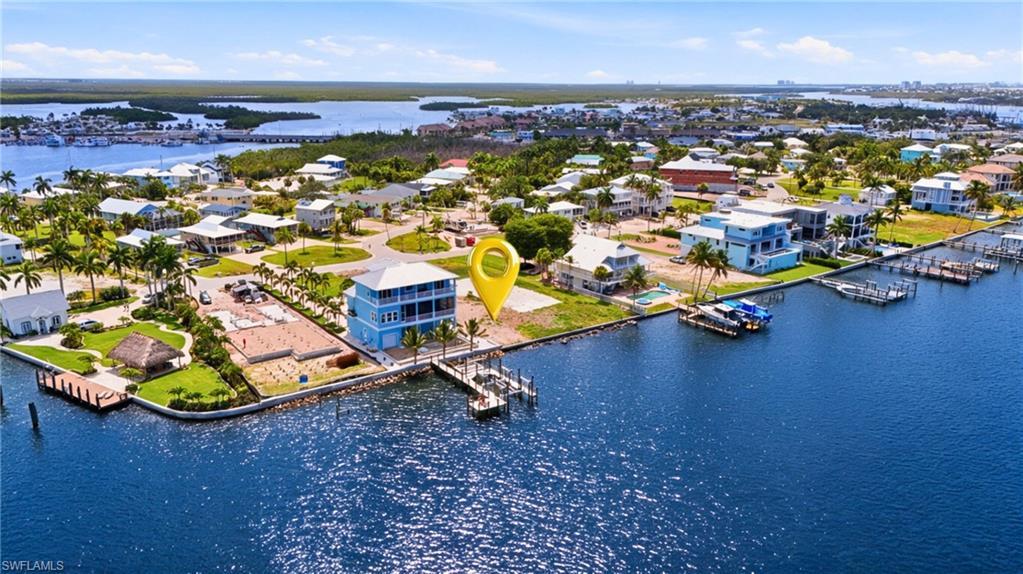 Waterfront property featuring a three-story structure with multiple balconies, a private dock system, and a surrounding tropical landscape with palm trees- Virtually Edited Image