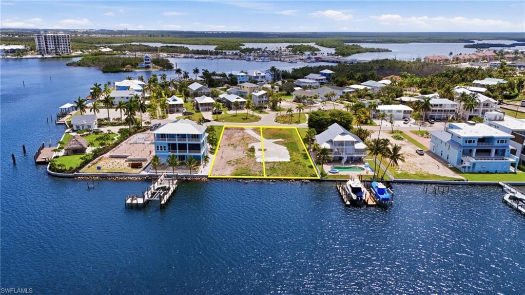 Waterfront lot featuring a cleared building area, direct water access, and existing surrounding residential properties - Virtually Edited Image